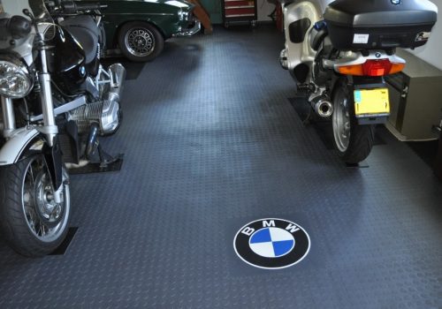BMW motorbikes parked in a garage with grey flooring tiles